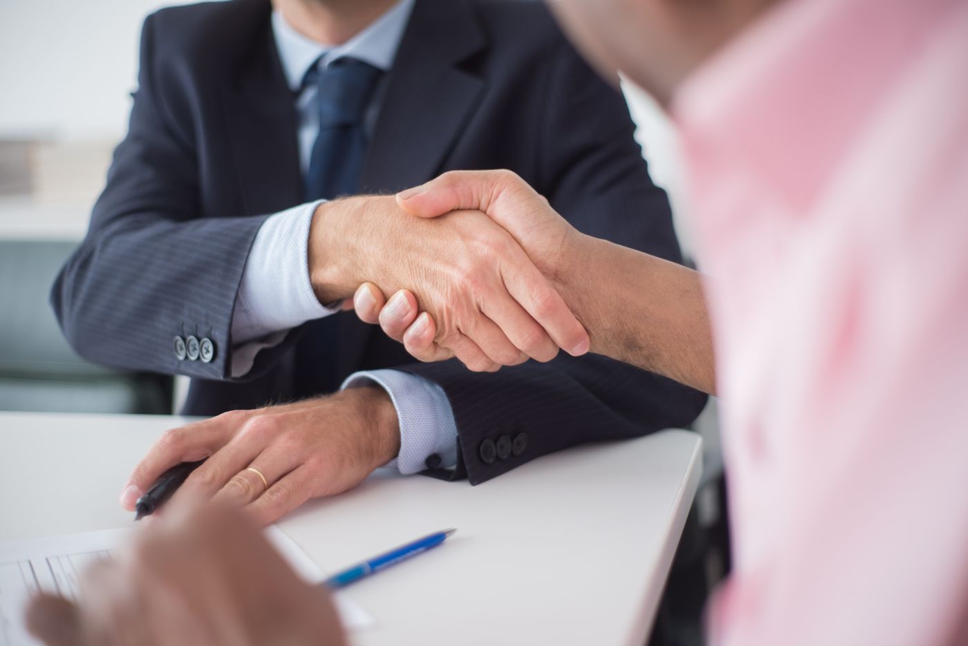 Two executives shaking hands across a desk