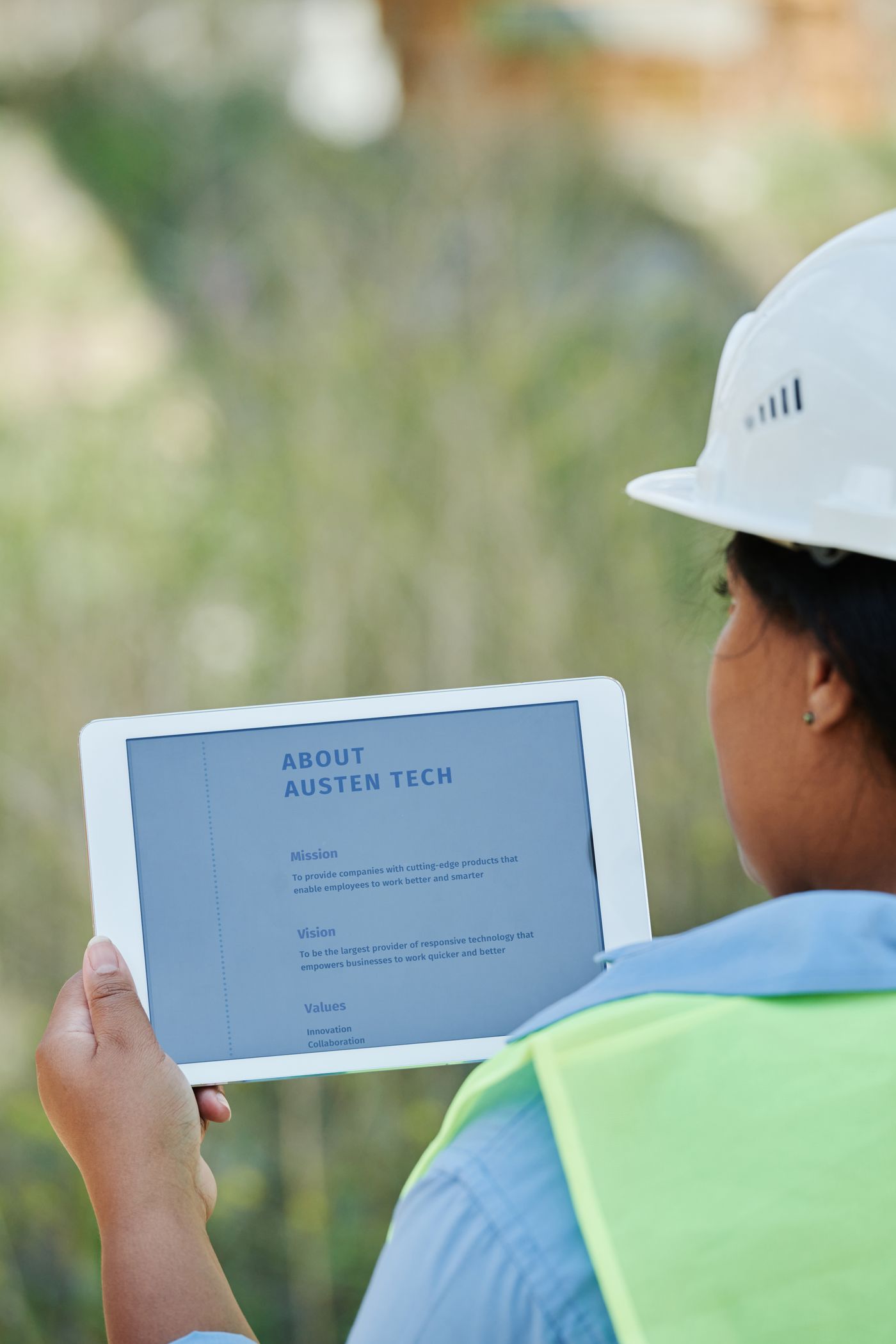 Field worker in a hard hat checking data on a tablet