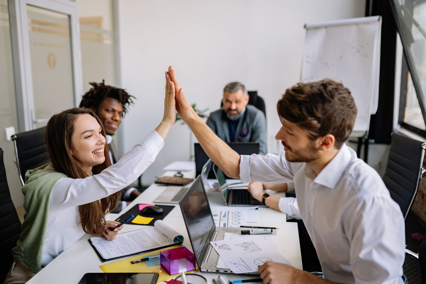 Colleagues celebrating with a high five during a team meeting