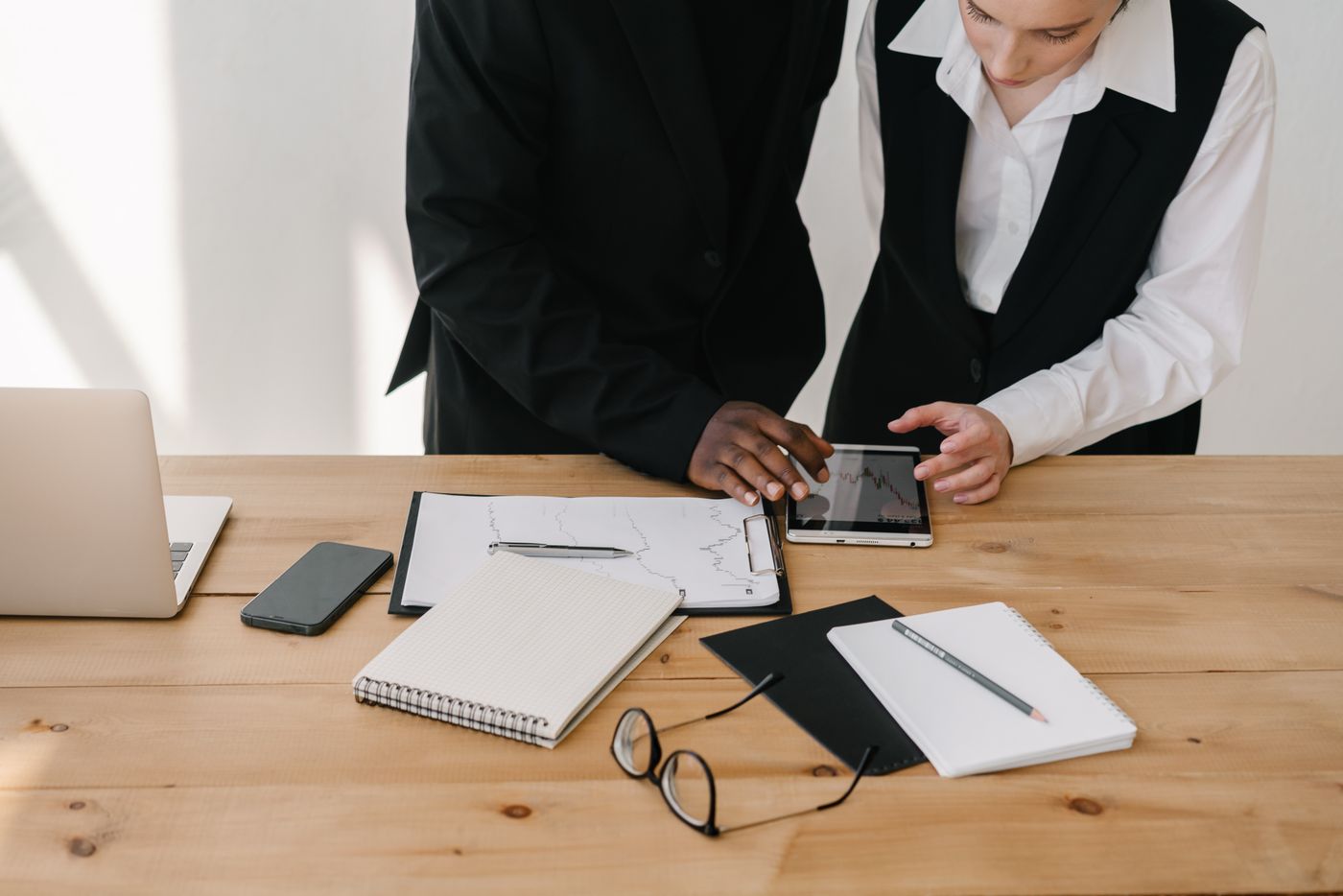 Colleagues reviewing documents and a tablet at a desk
