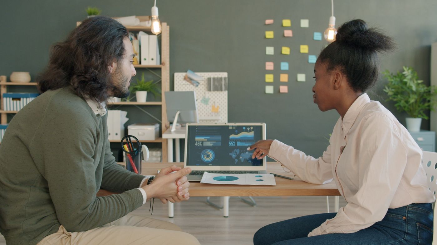 Two colleagues discussing information on screens at a table