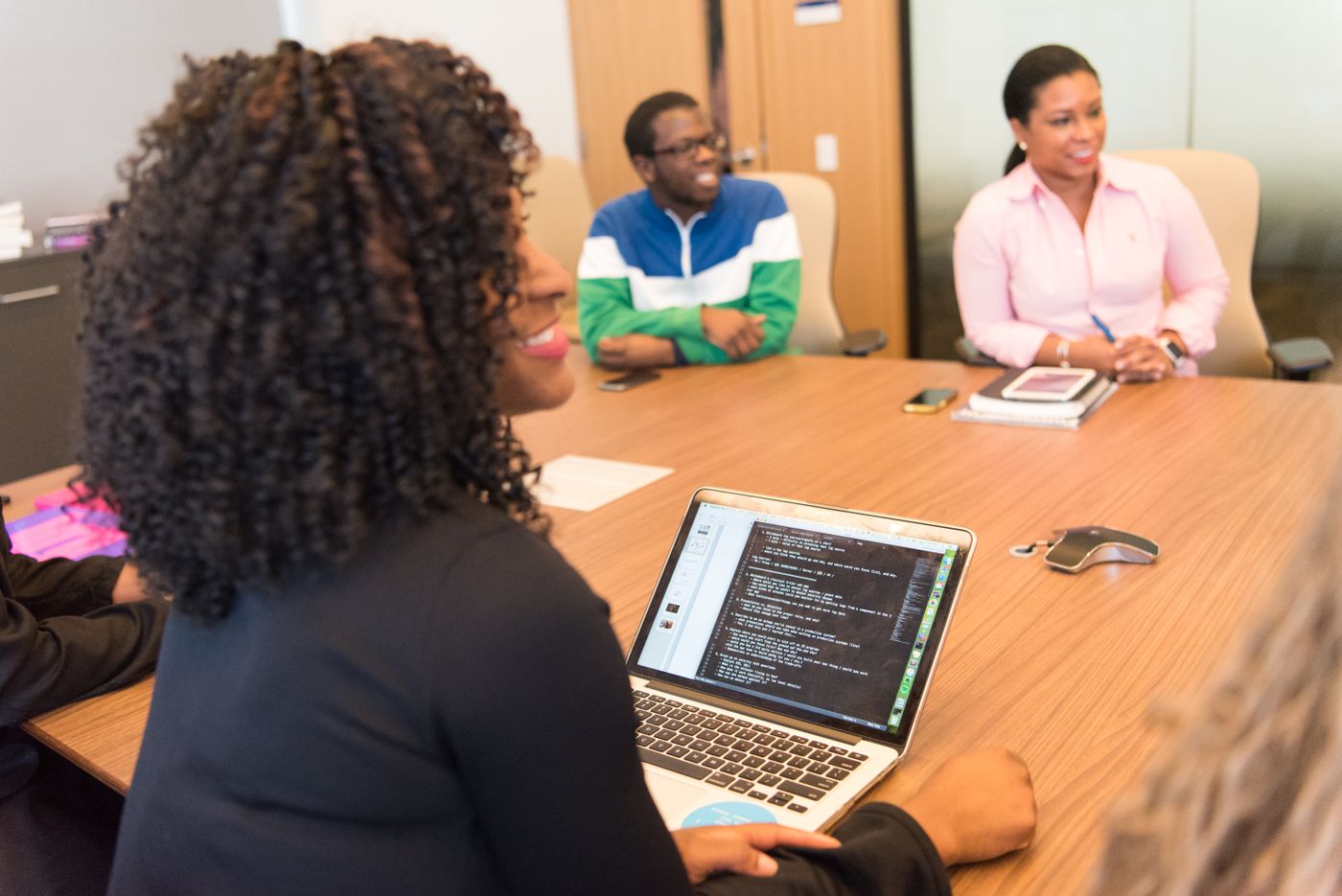 Team around a conference table with a laptop showing code