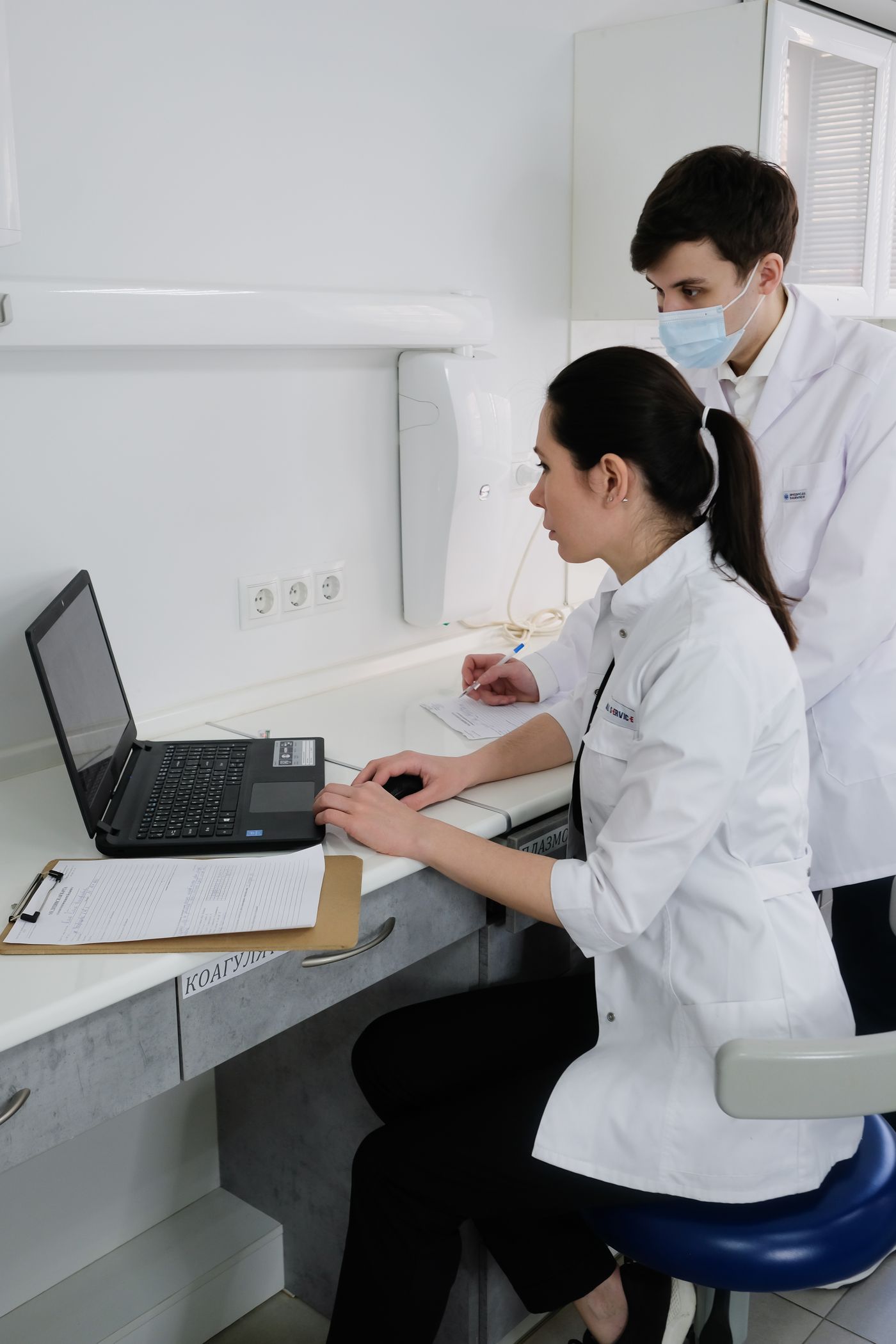 Two lab staff reviewing results on a laptop
