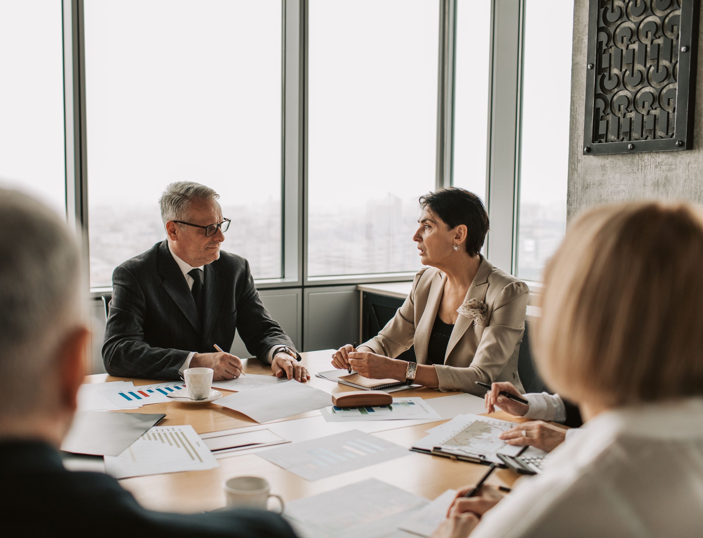 Senior executives discussing documents across a meeting table in a bright office