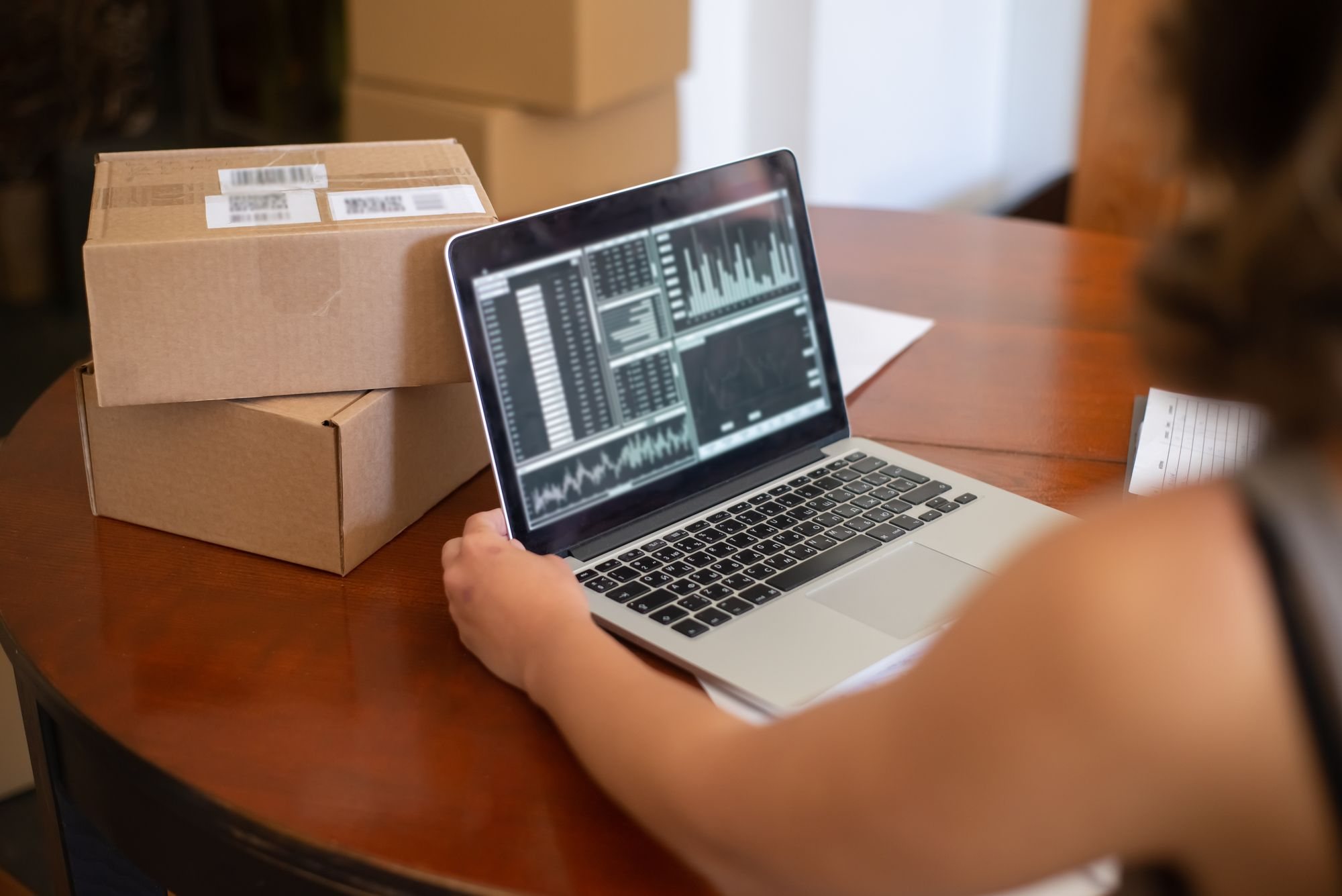 Laptop showing sales charts on a table beside packed parcels