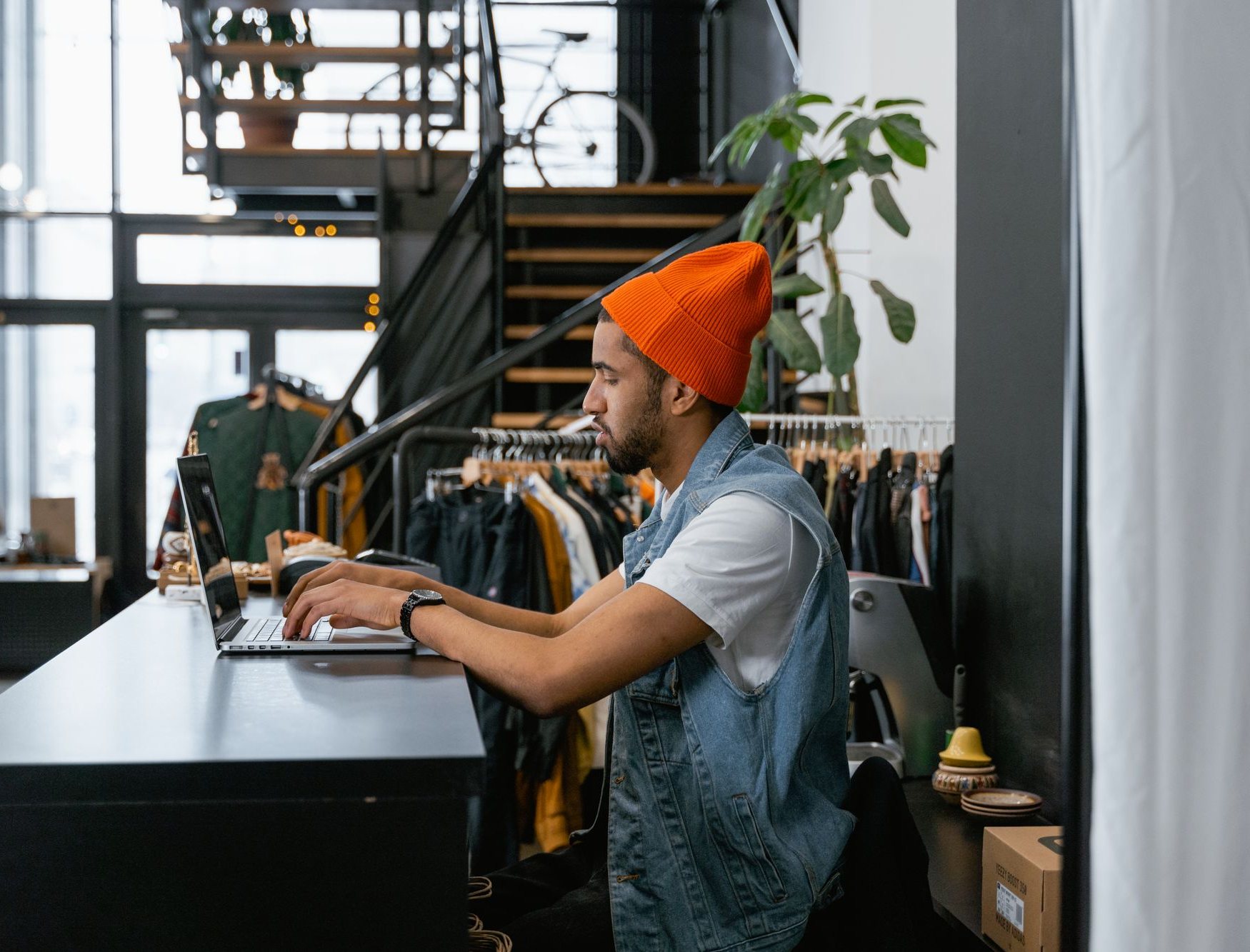 Store manager working on a laptop at the counter of a clothing store