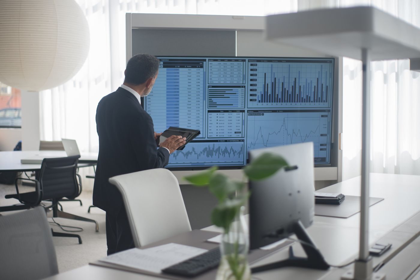 Analyst reviewing reporting dashboards on large screens
