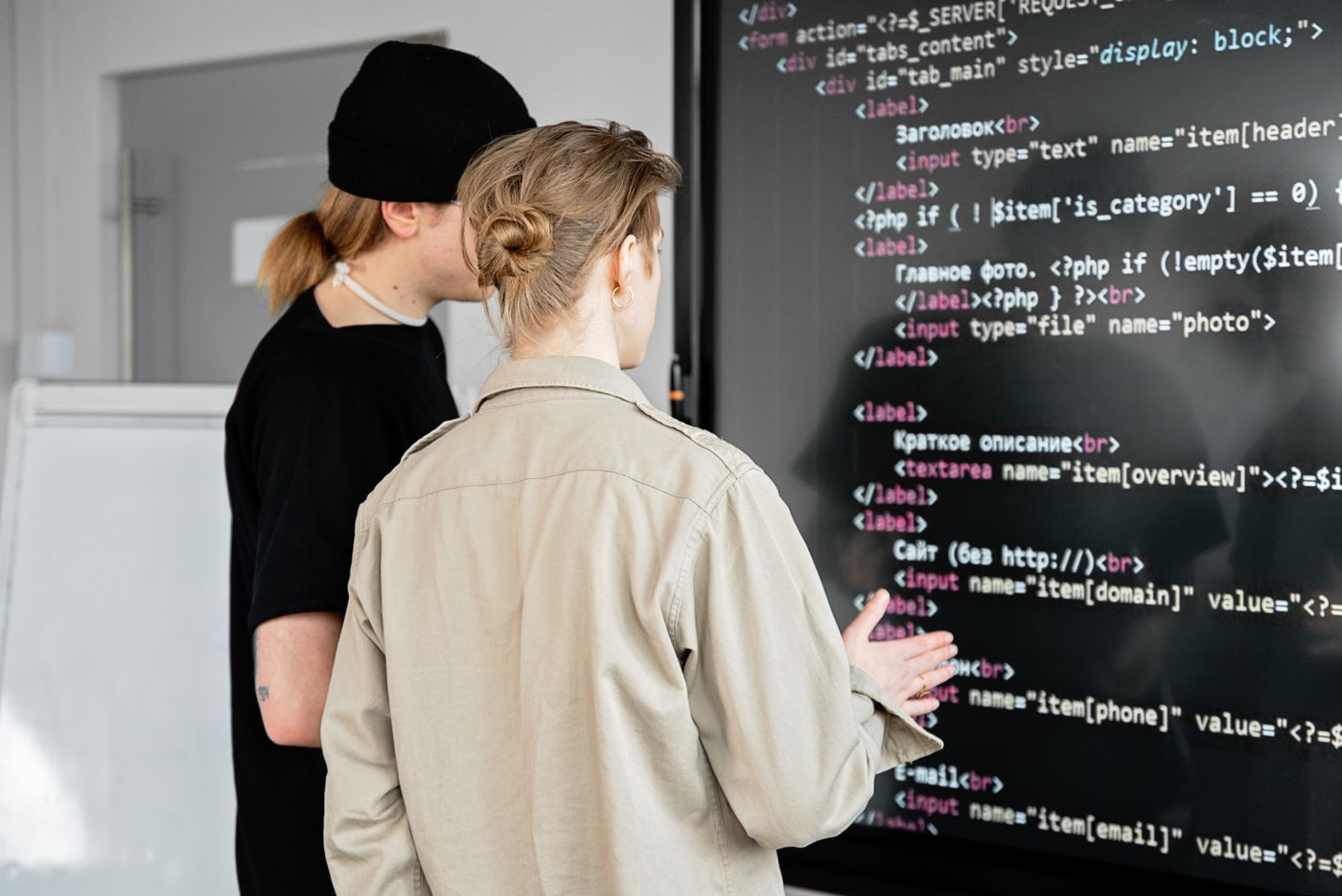 Two developers reviewing API code on a large screen
