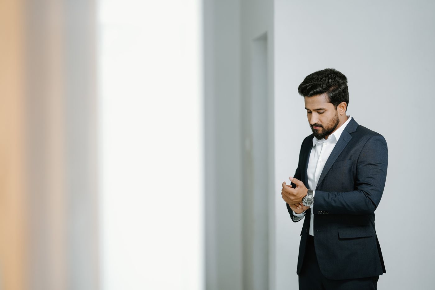 Business leader in a tailored suit adjusting his cuff in an office
