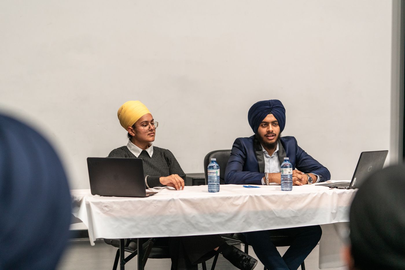 Two recruiters at a hiring desk with laptops during a campus recruitment event