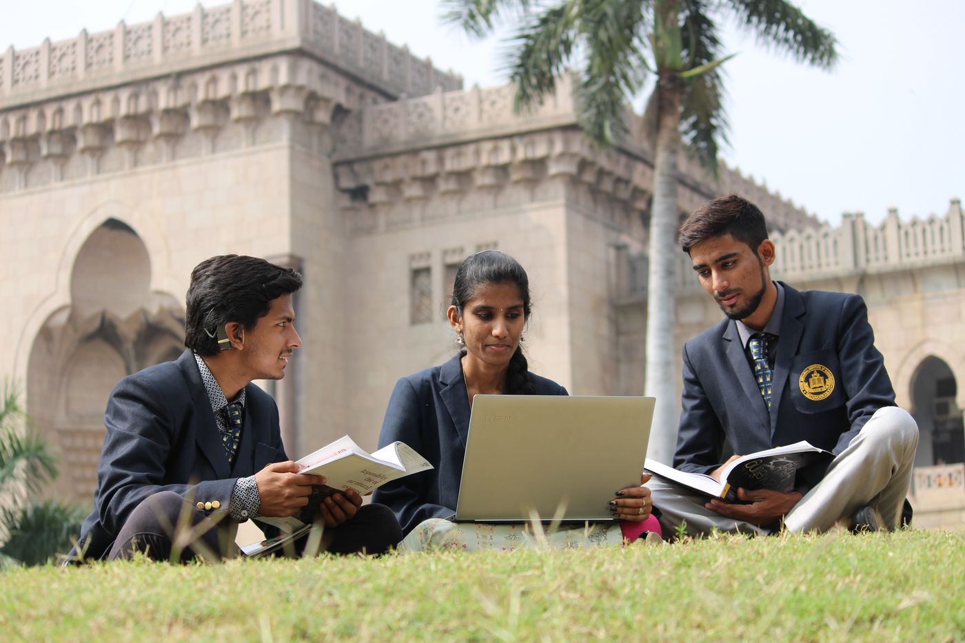 University students studying together with a laptop on a campus lawn