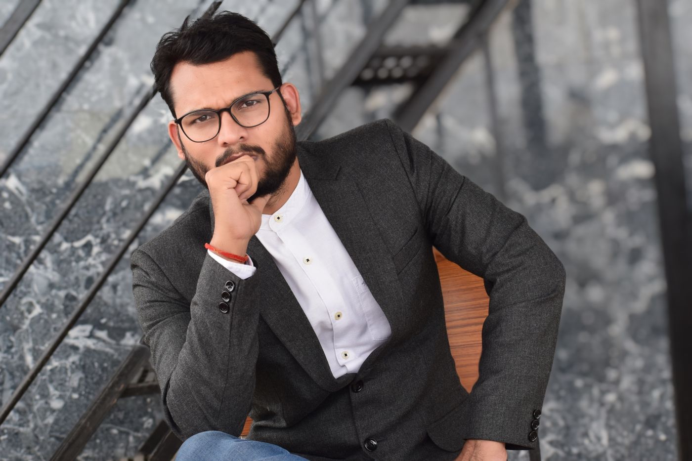 Executive in glasses and a blazer seated in thought