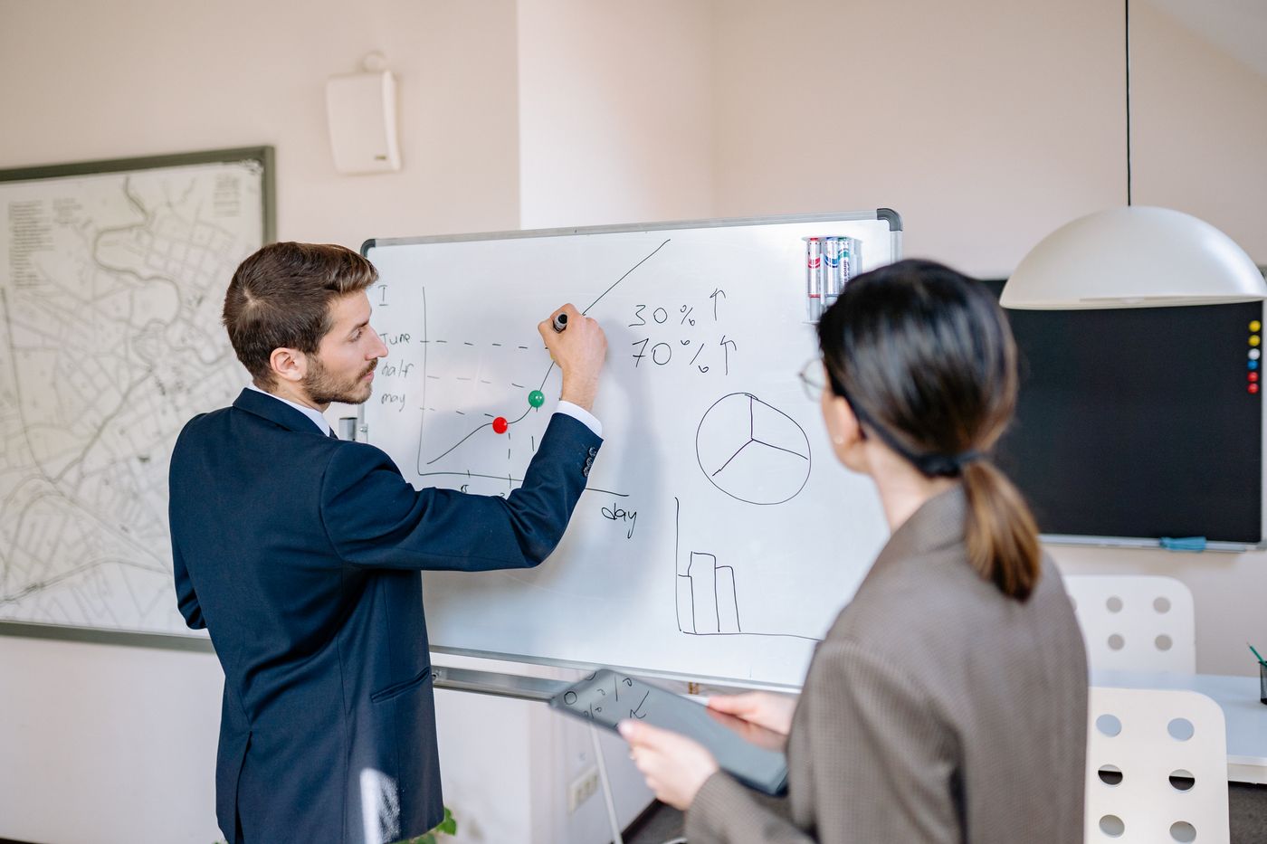 Consultant sketching a solution plan on a whiteboard for a client