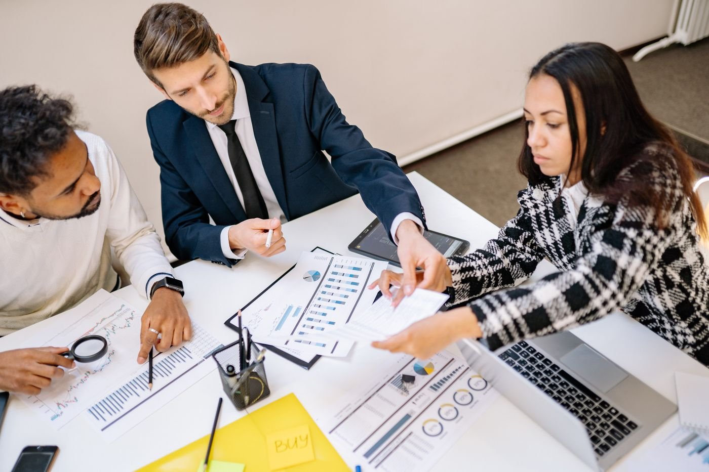 Three colleagues reviewing charts and plans together at a bright office desk