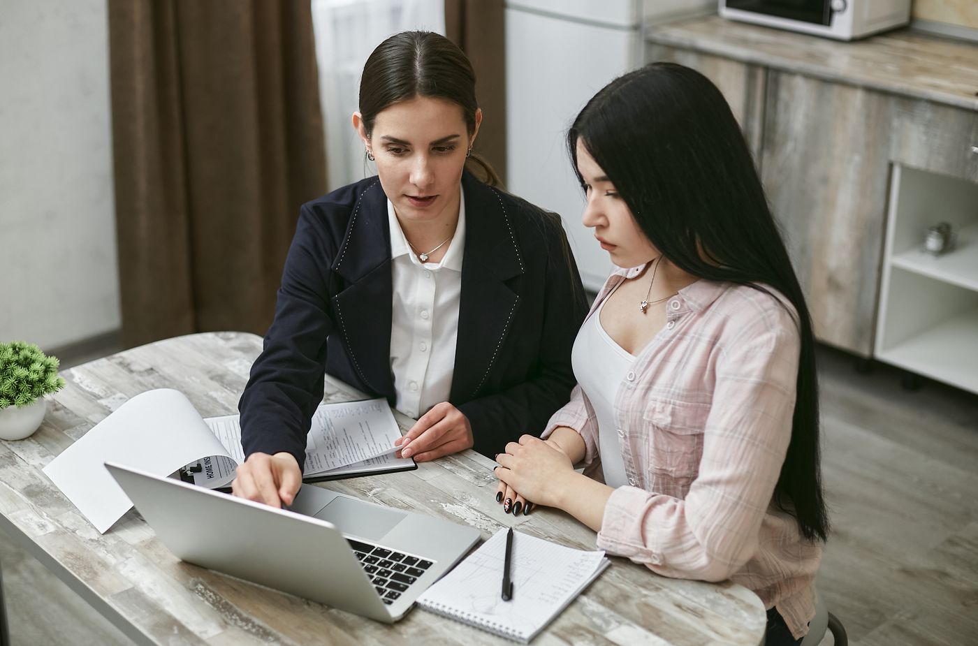Two colleagues reviewing a workflow together on a laptop