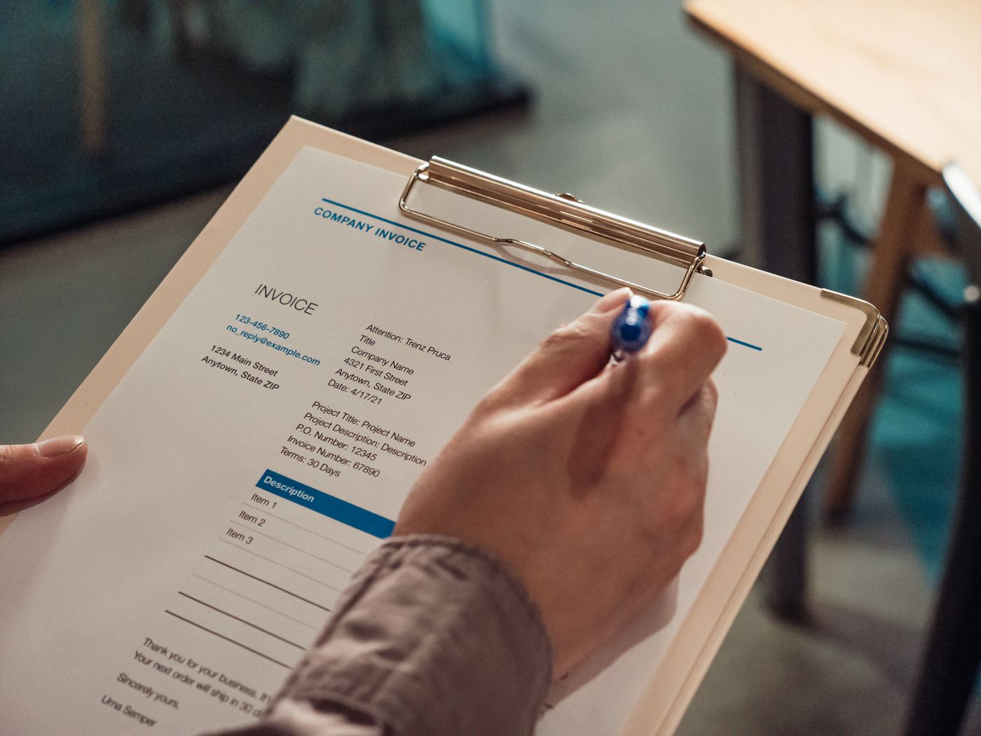Invoice on a clipboard being checked with a pen