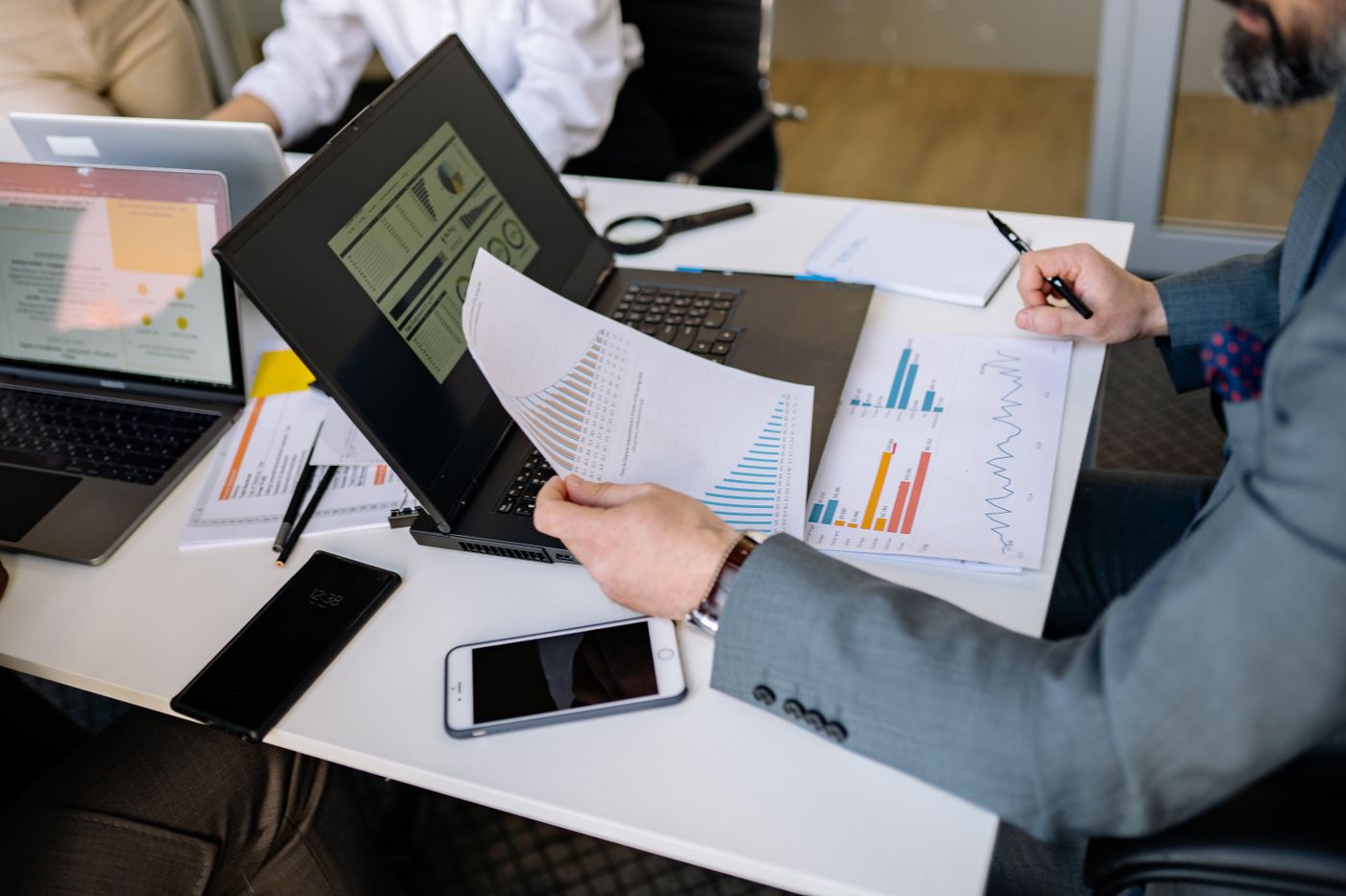 Business reports and charts reviewed beside a laptop