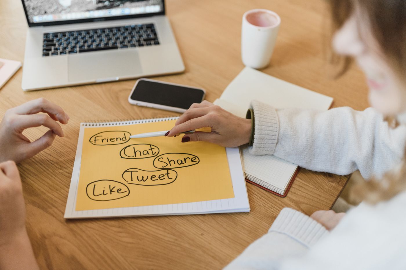 Two colleagues planning an employer brand social media campaign with a laptop and notebook