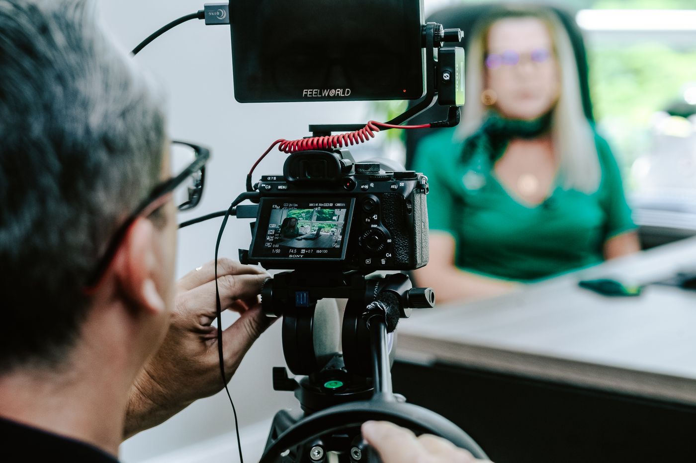 Camera operator filming an employee story interview in an office