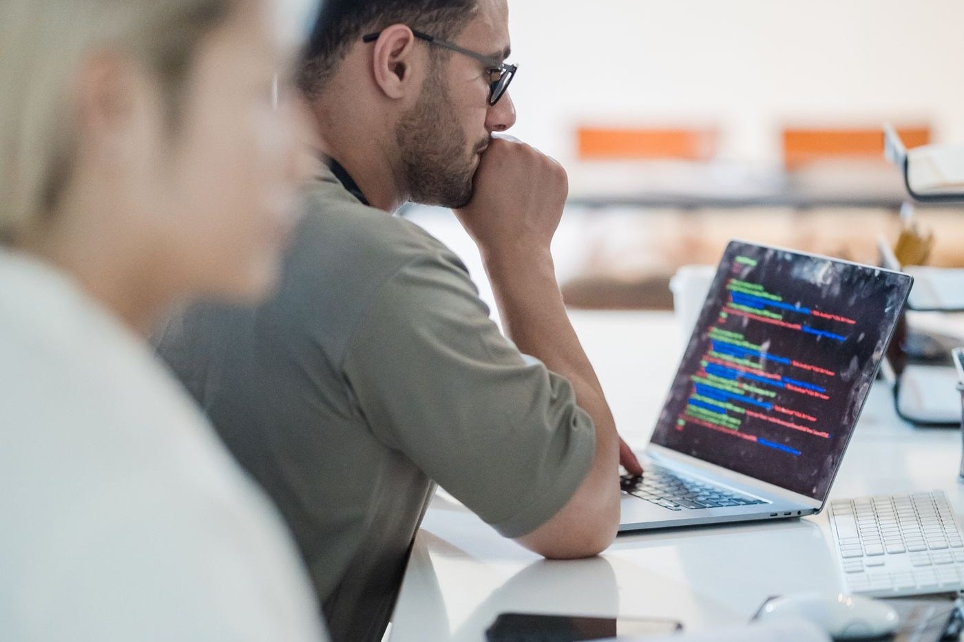 Software engineer reviewing code on a laptop beside a colleague