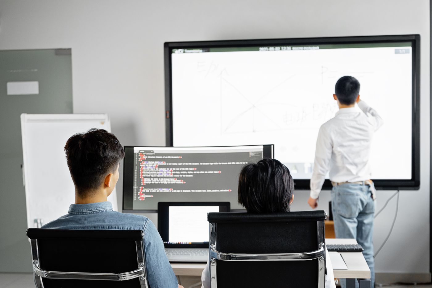 Engineers configuring a system on a large screen and a workstation of code