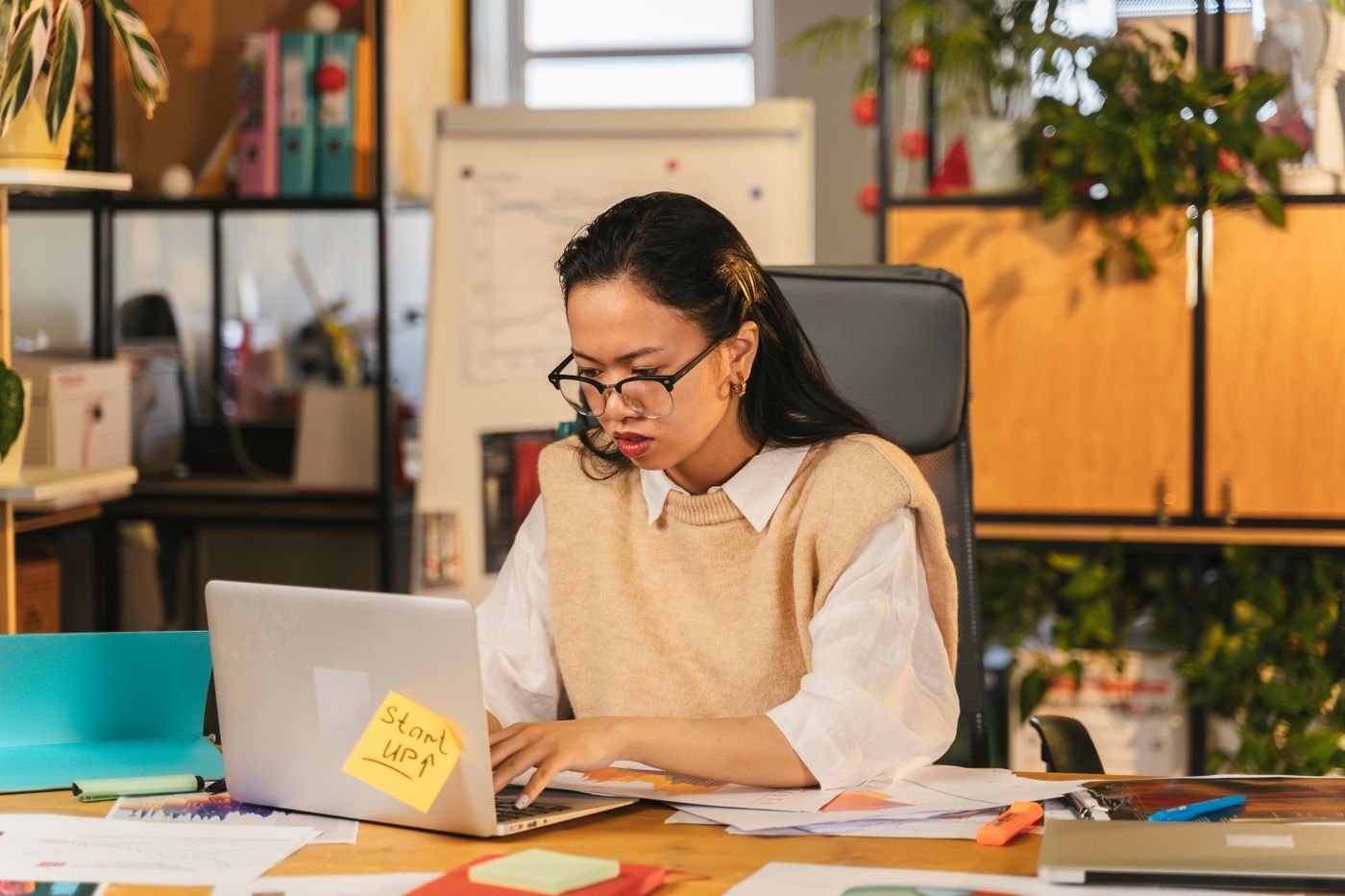 Professional working on a laptop in front of a whiteboard of connected process notes