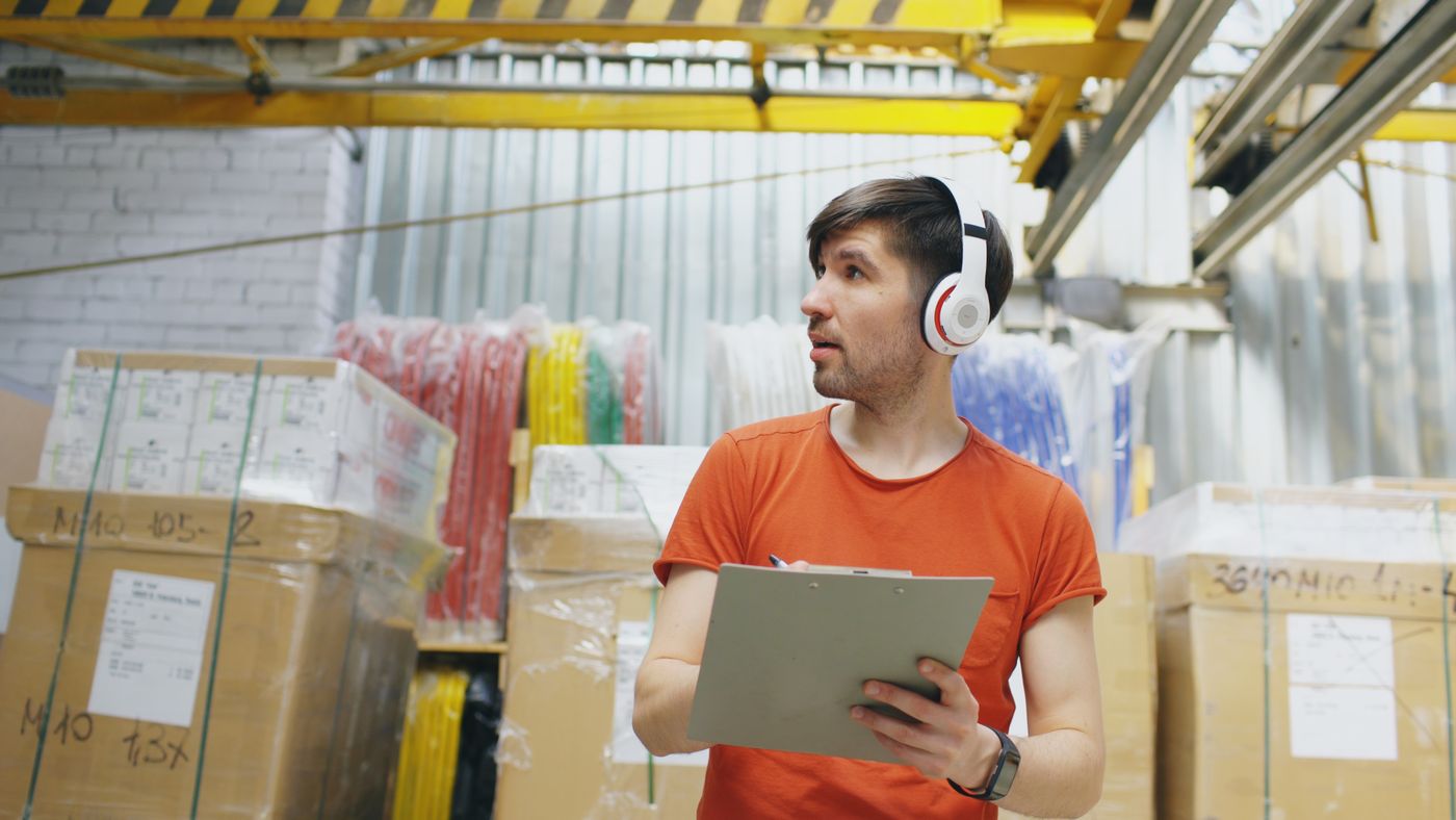 Warehouse worker checking inventory on a tablet between stacked stock