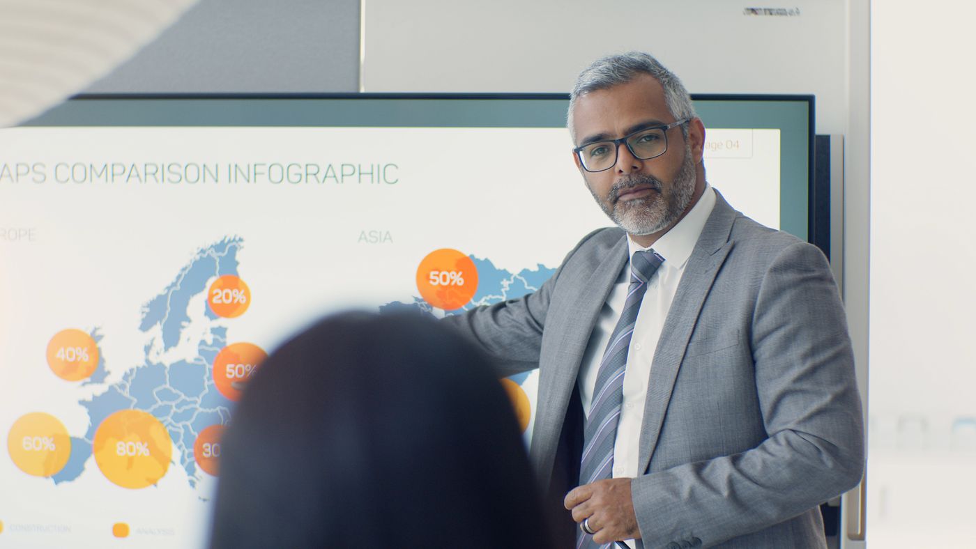 Senior executive presenting a market map on a screen to colleagues