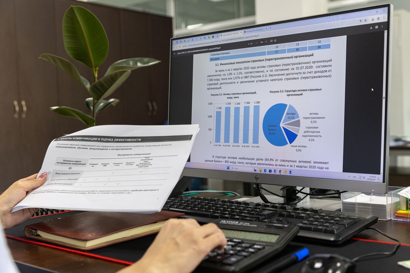 Printed report held beside a monitor showing charts and a data summary