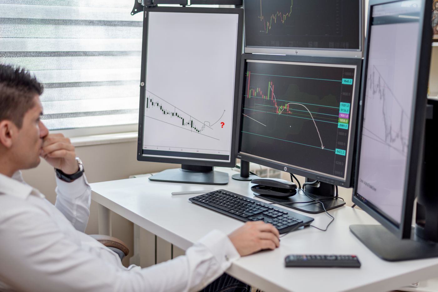 Analyst reviewing reports across several monitors