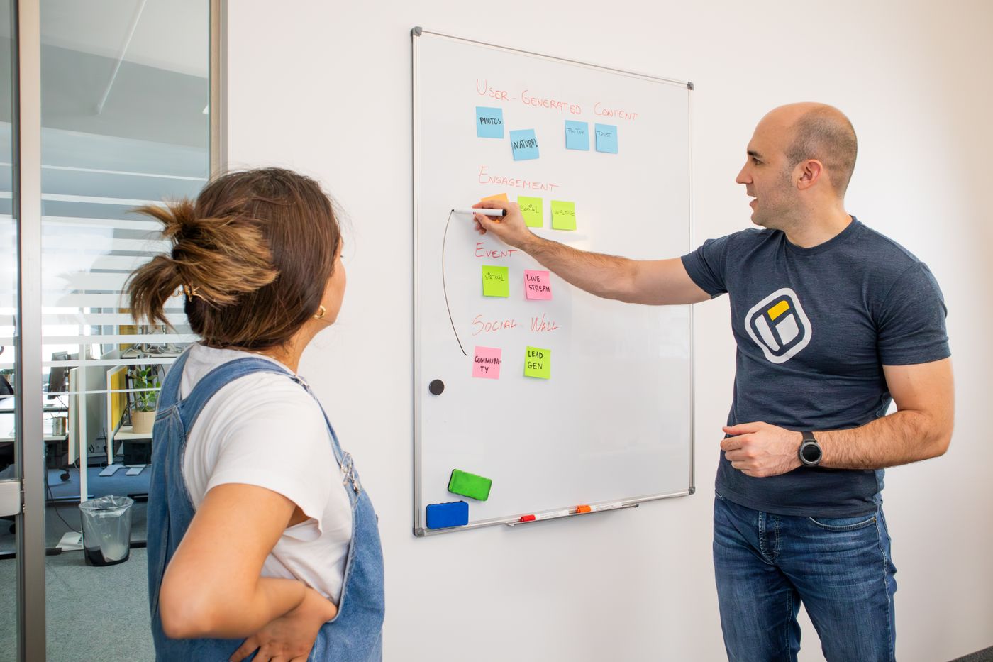 Consultant mapping a solution plan on a whiteboard of sticky notes with a colleague
