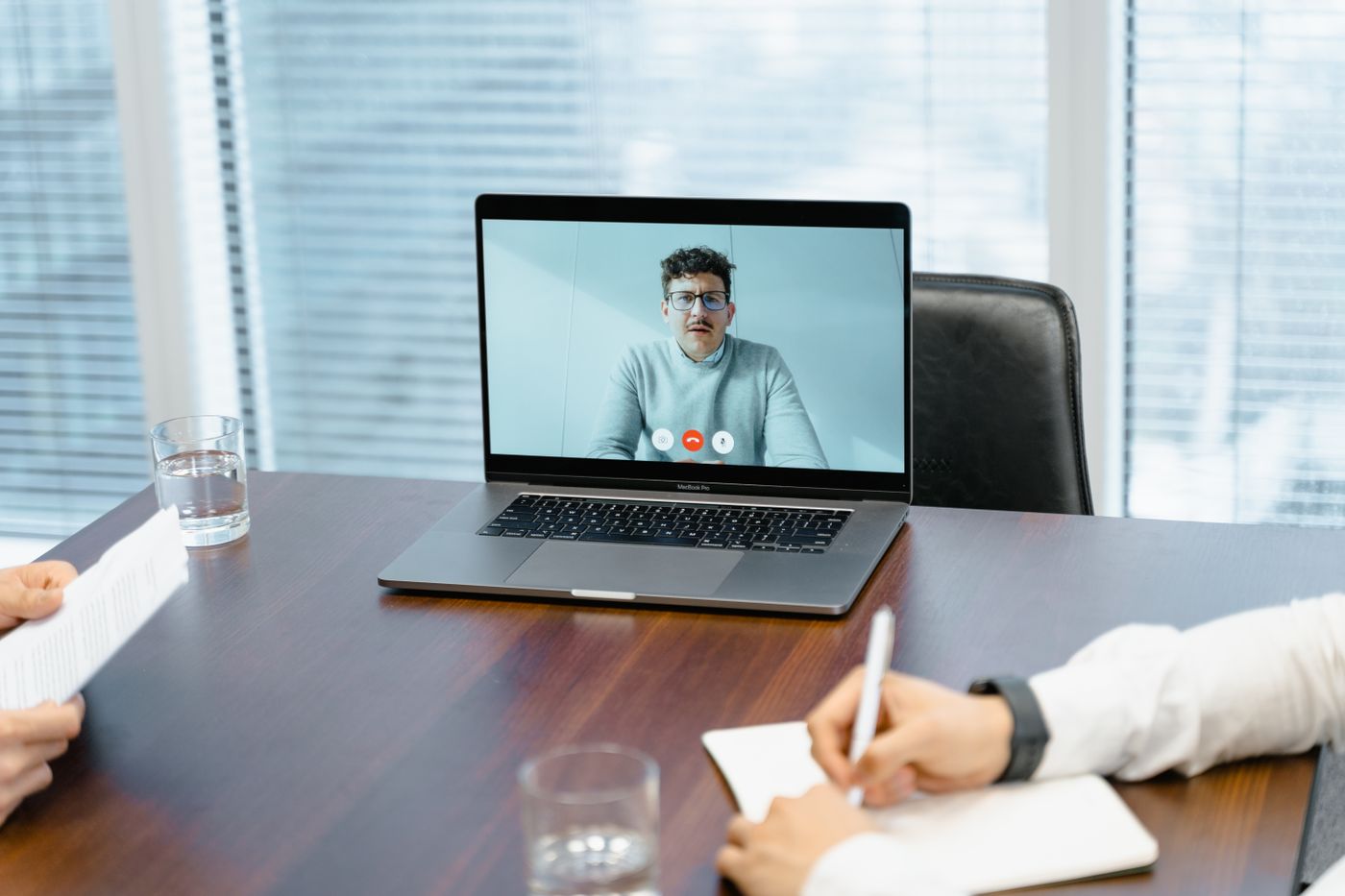 Interviewers taking notes during a candidate video call on a laptop