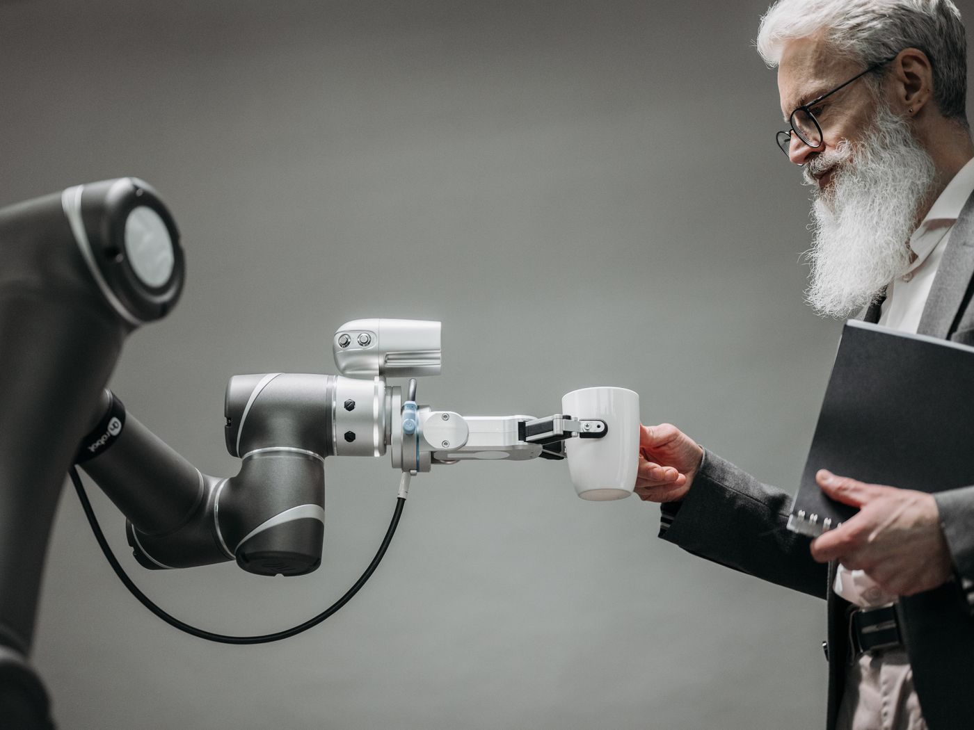 Robotic arm handing a cup to a person in an office