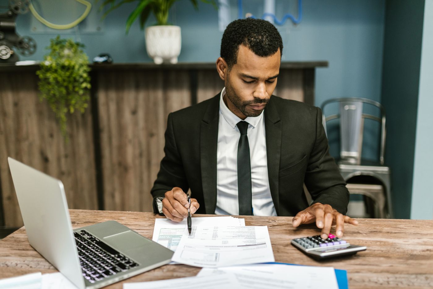 Accountant working through documents with a calculator and laptop