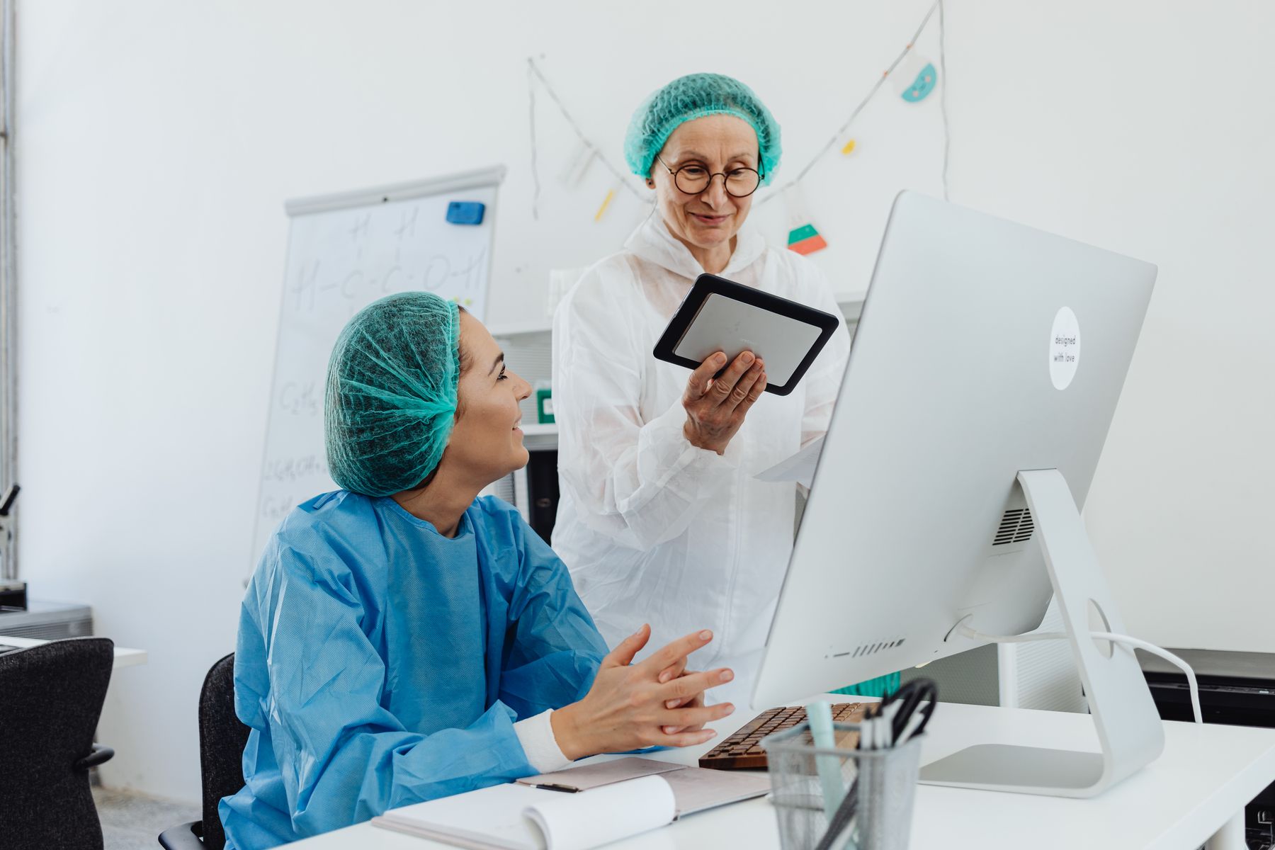 Clinicians reviewing information on a tablet beside a computer