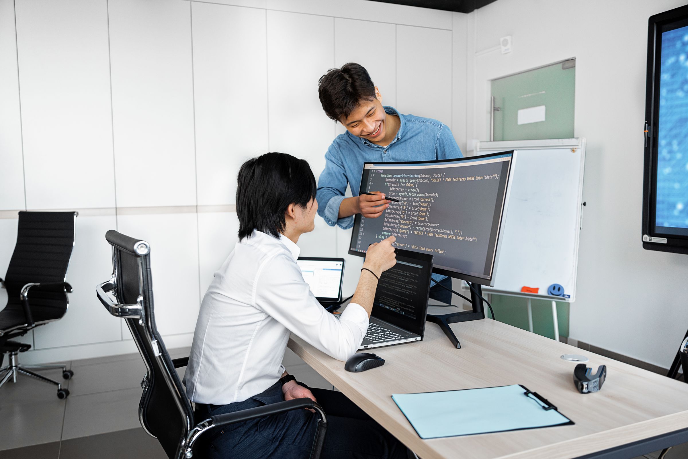 Two colleagues working through a workflow at a monitor