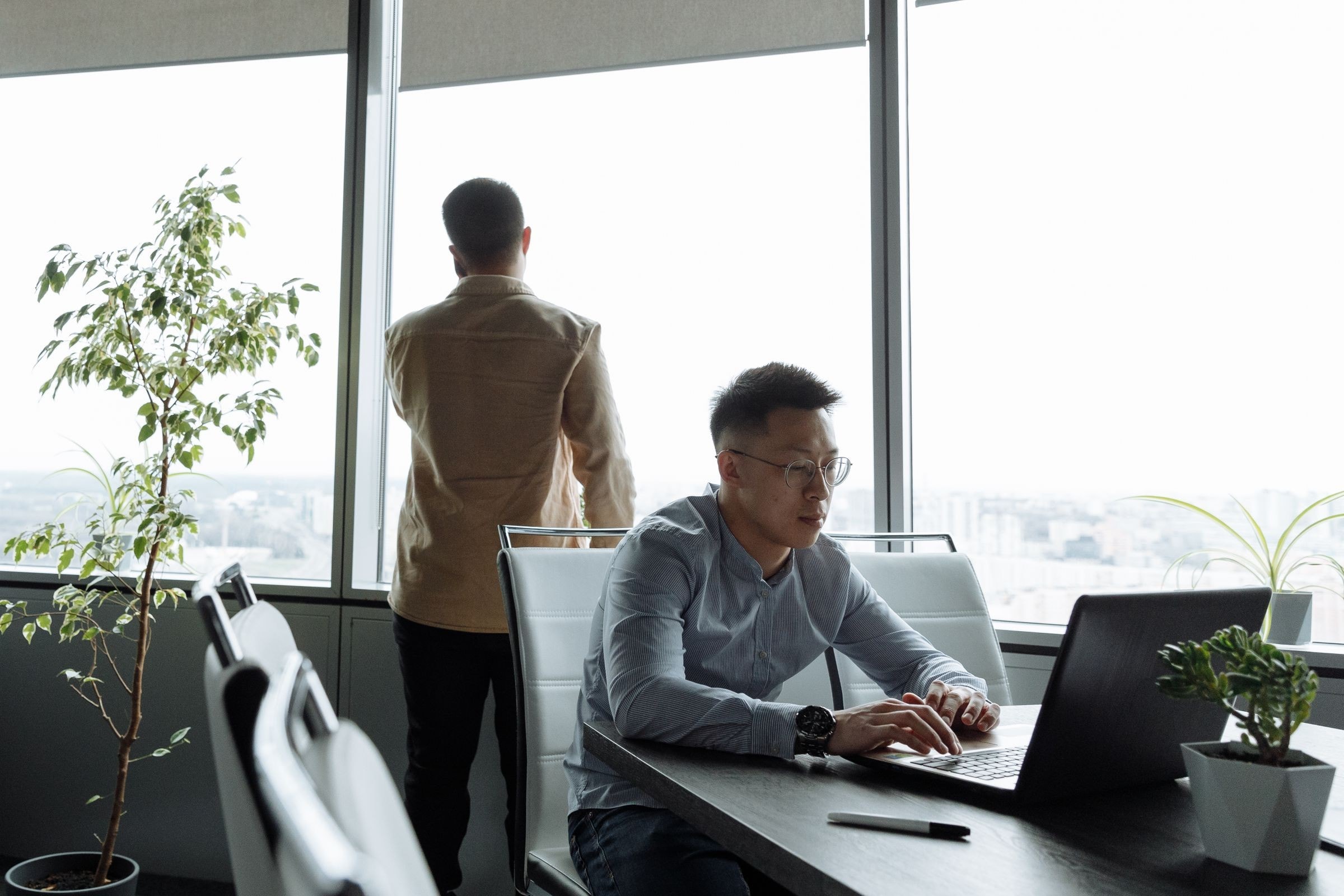 Professional working on a laptop in a bright office with city views