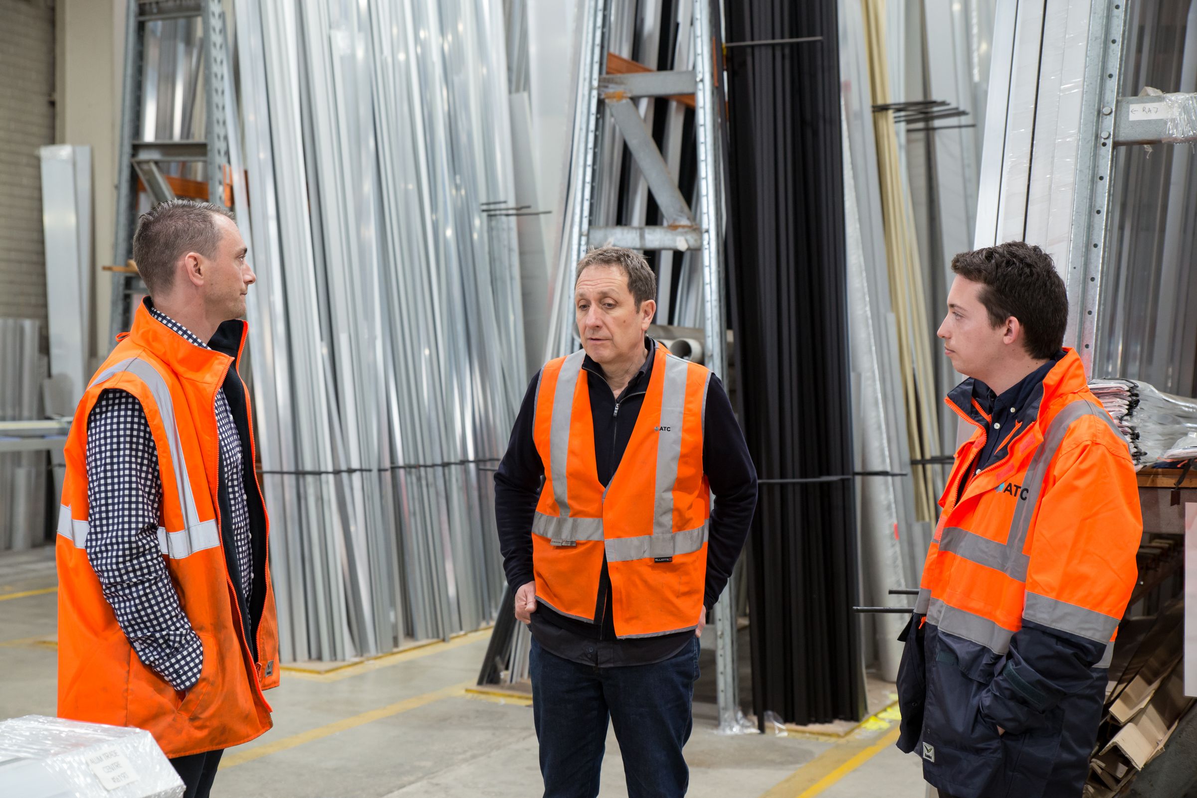 Operations team in safety vests discussing work on a manufacturing plant floor
