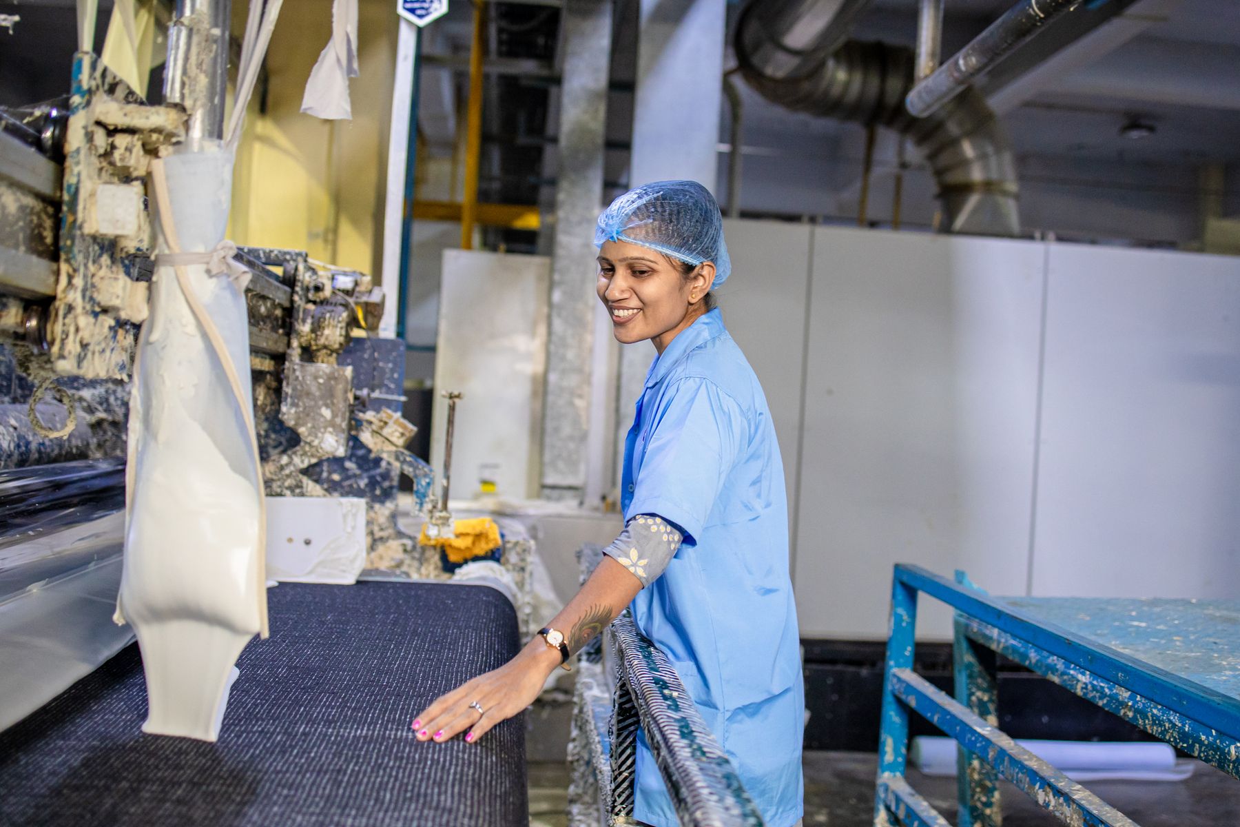 Machine operator smiling beside production equipment on a factory floor
