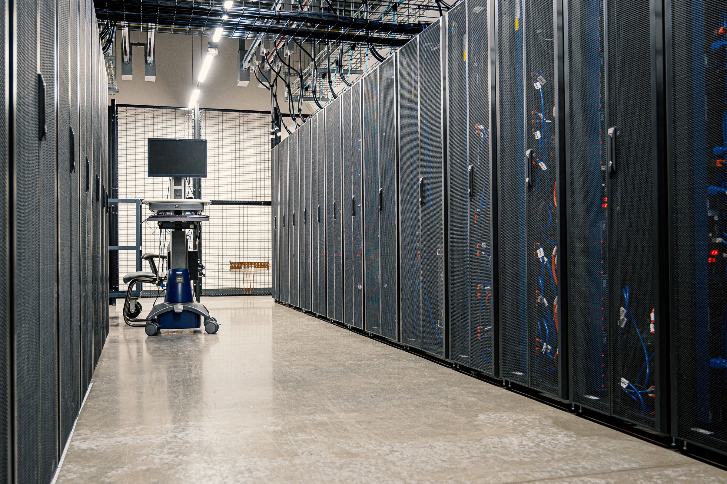 Row of data centre cabinets with a monitoring workstation at the end of the aisle