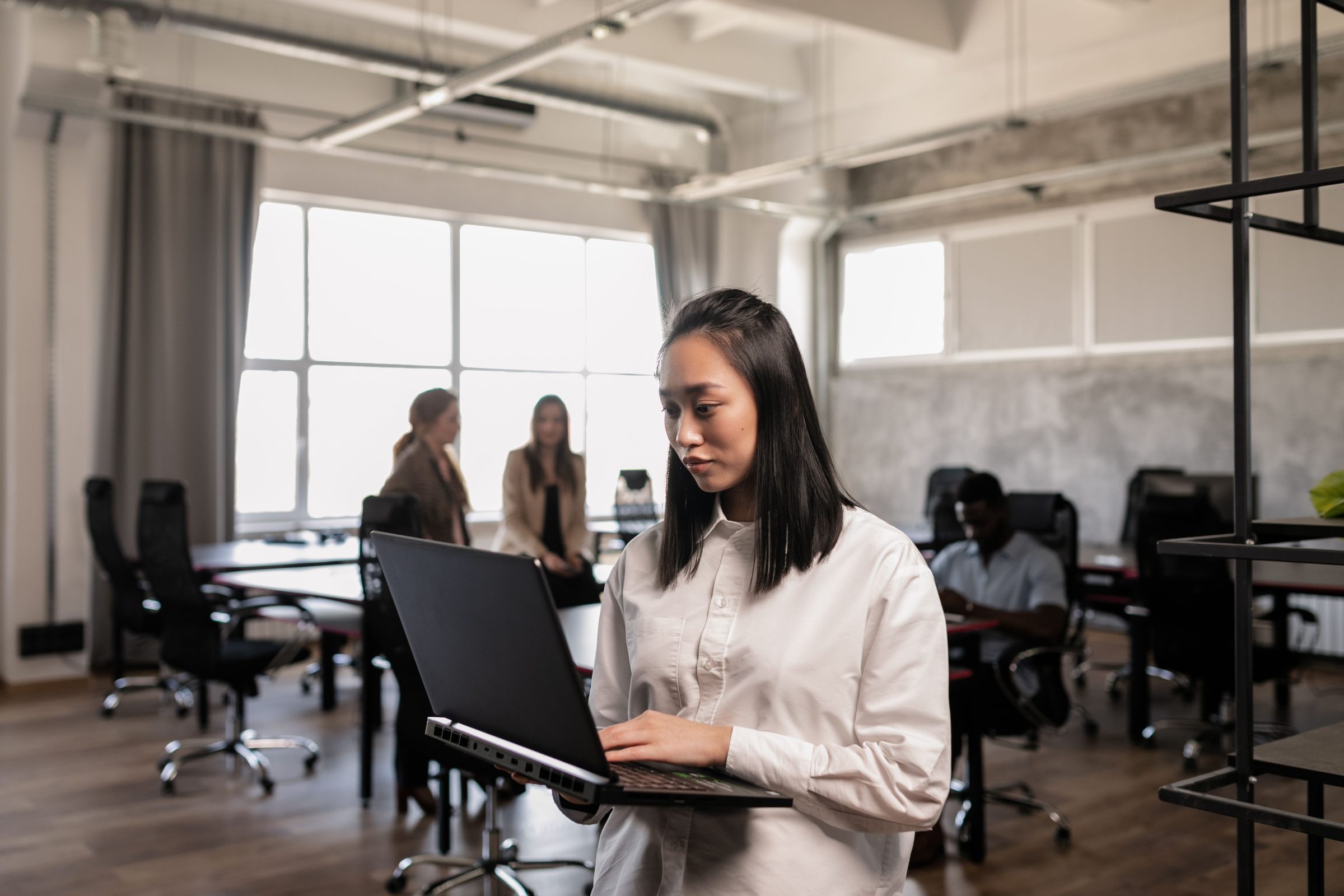 Professional working on a laptop in a bright open-plan office