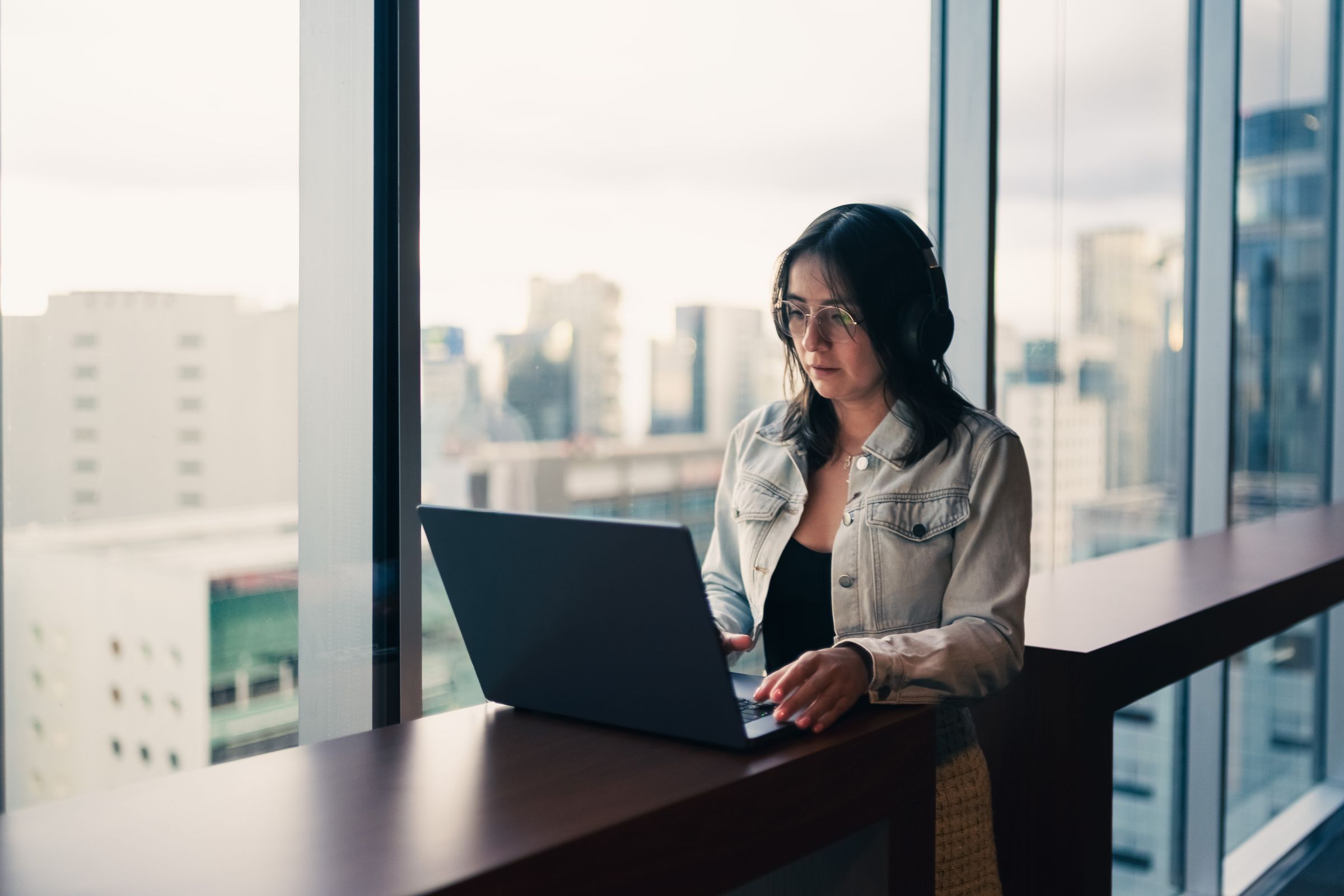 Professional working through her CRM pipeline by a city-view window