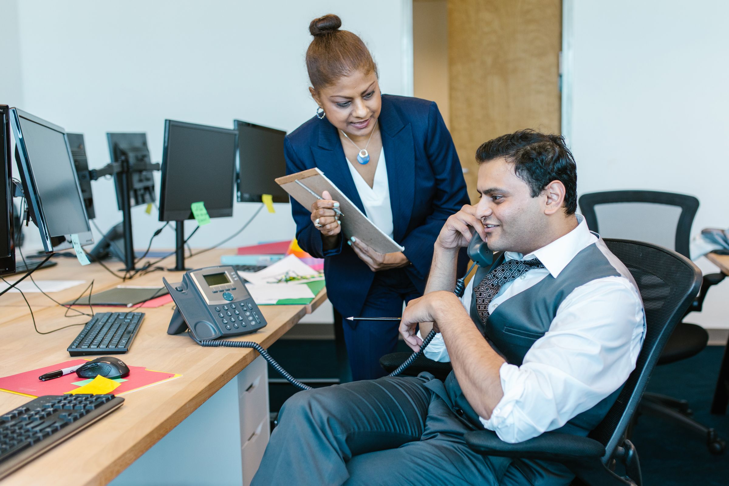 Sales manager showing a rep a tablet at his desk