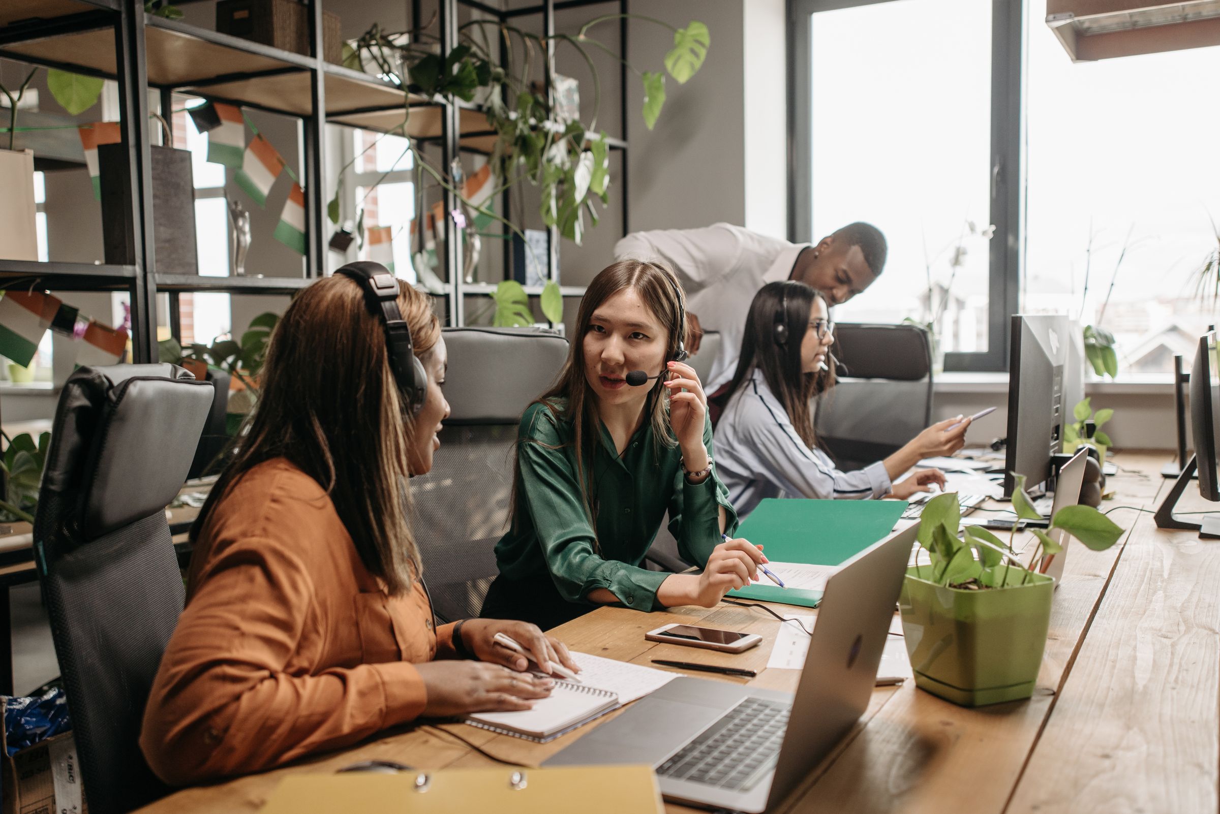 Customer and sales teams working together at laptops in a bright open-plan office