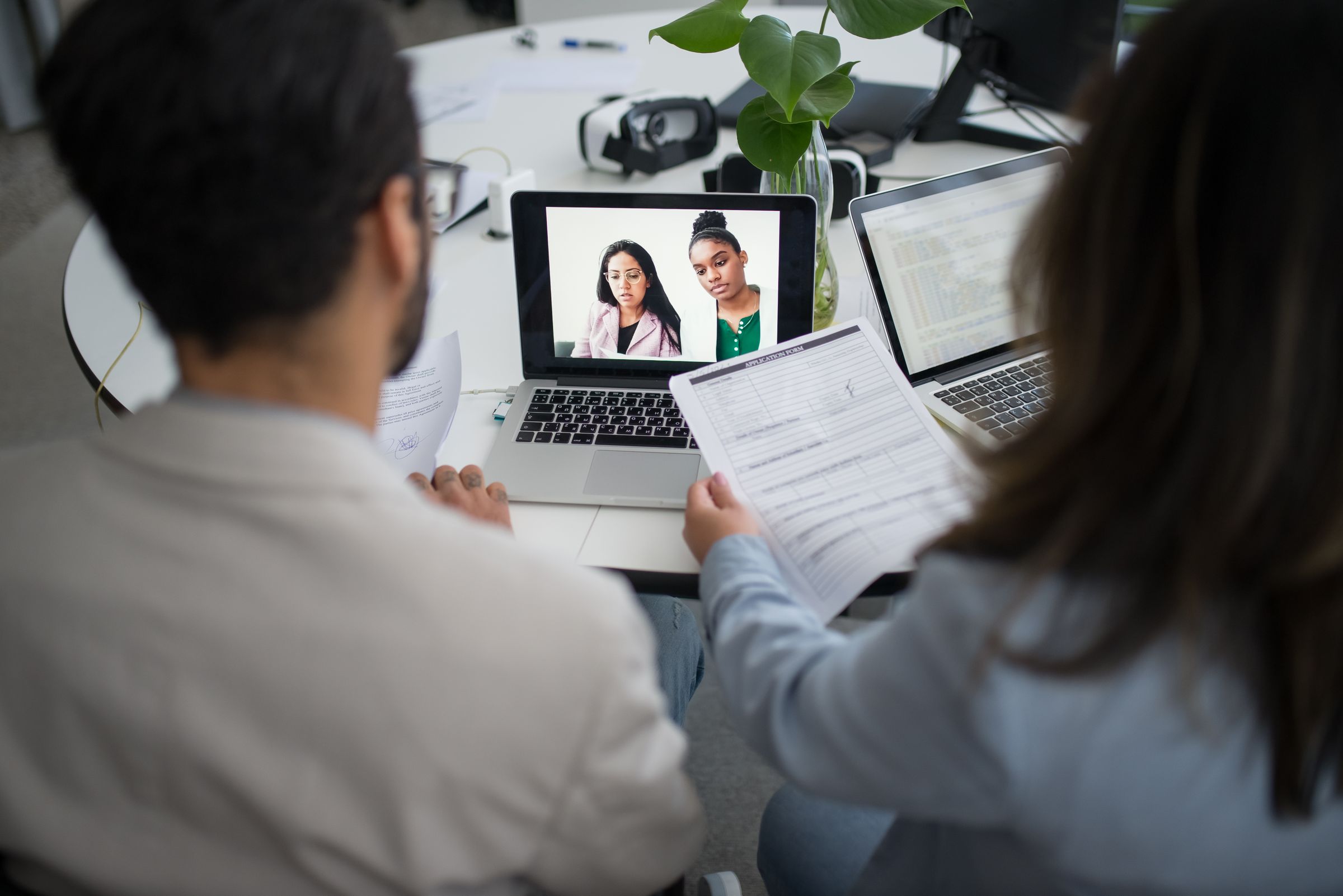 Recruiters running a virtual candidate interview with a laptop and an application form