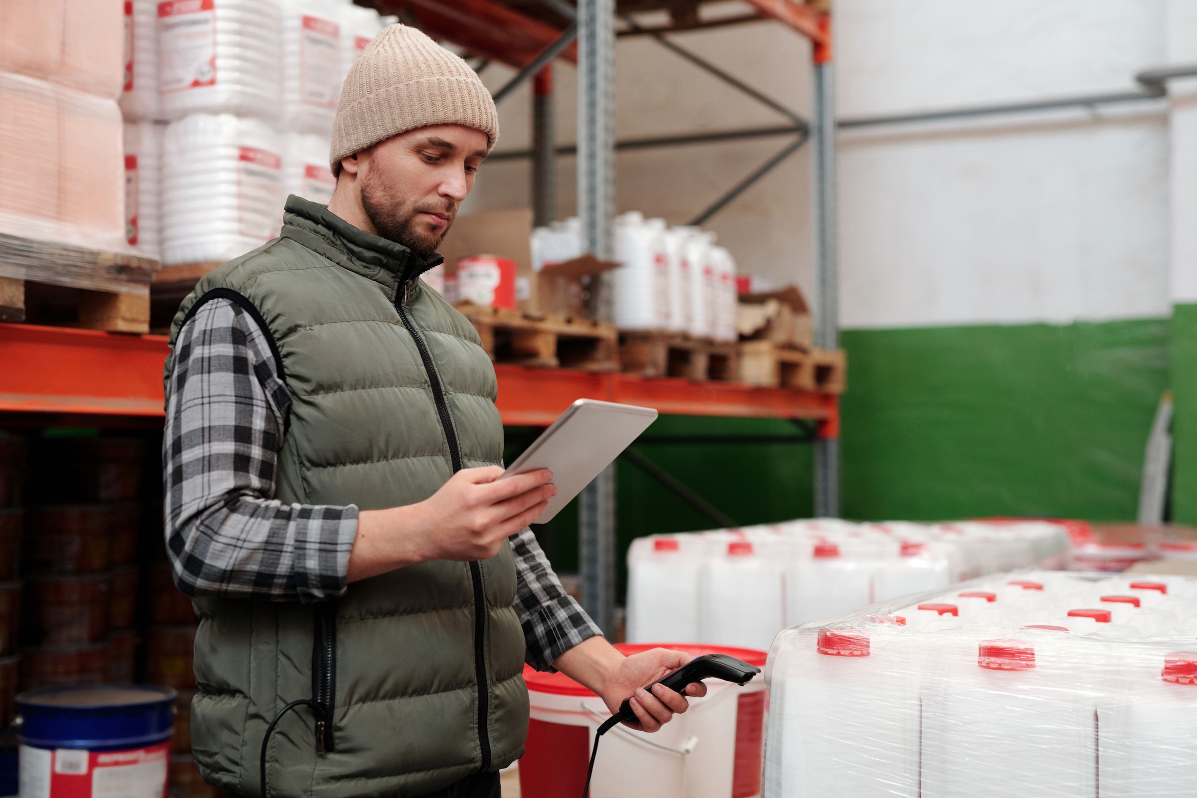 Warehouse worker scanning stock with a tablet between storage racks