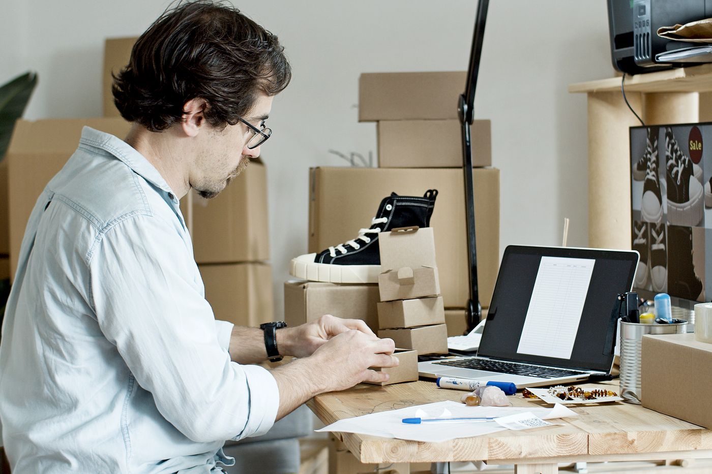 Online seller packing an order beside a laptop