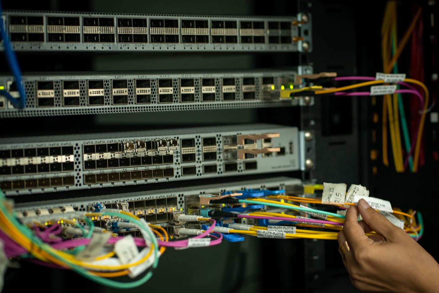 Hands connecting network cables in a data centre rack