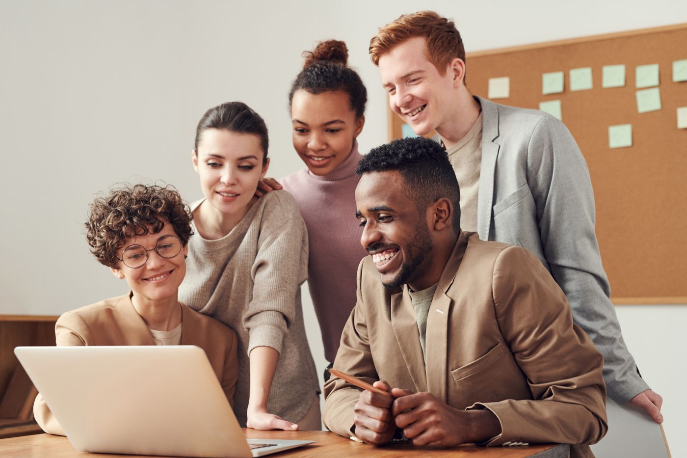 Team gathered around a laptop, smiling at what is on screen