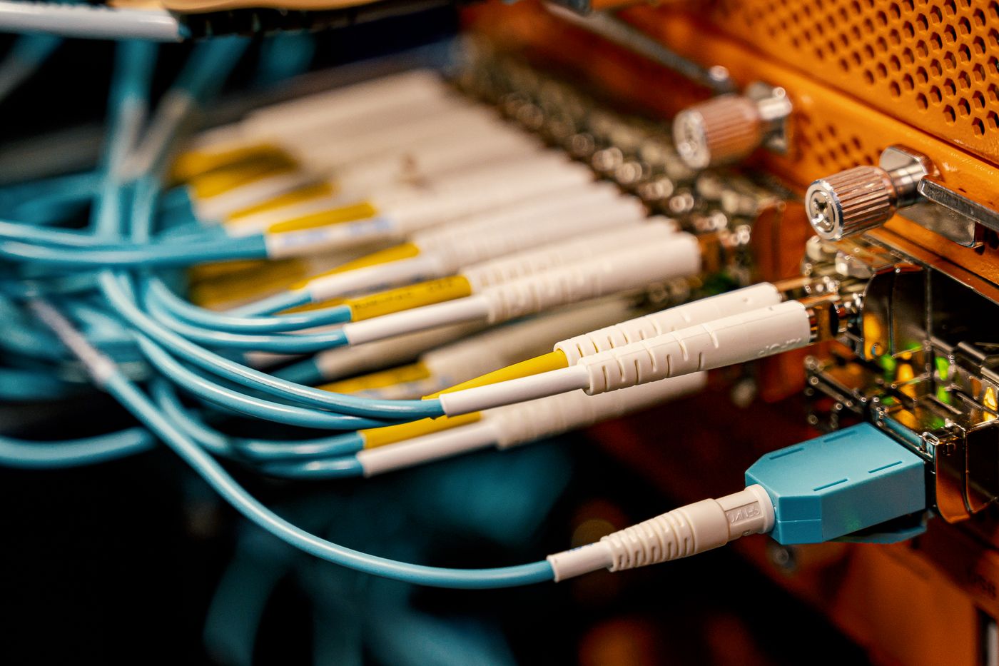 Close-up of fibre-optic connectors plugged into network hardware